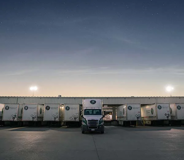 Old Dominion LTL trucks lined up at a freight terminal dock under a night sky.