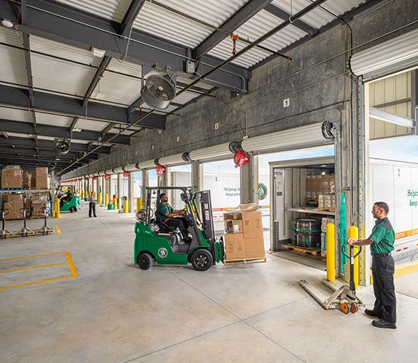ODFL workers loading freight at a service center dock with forklifts and pallet jacks.